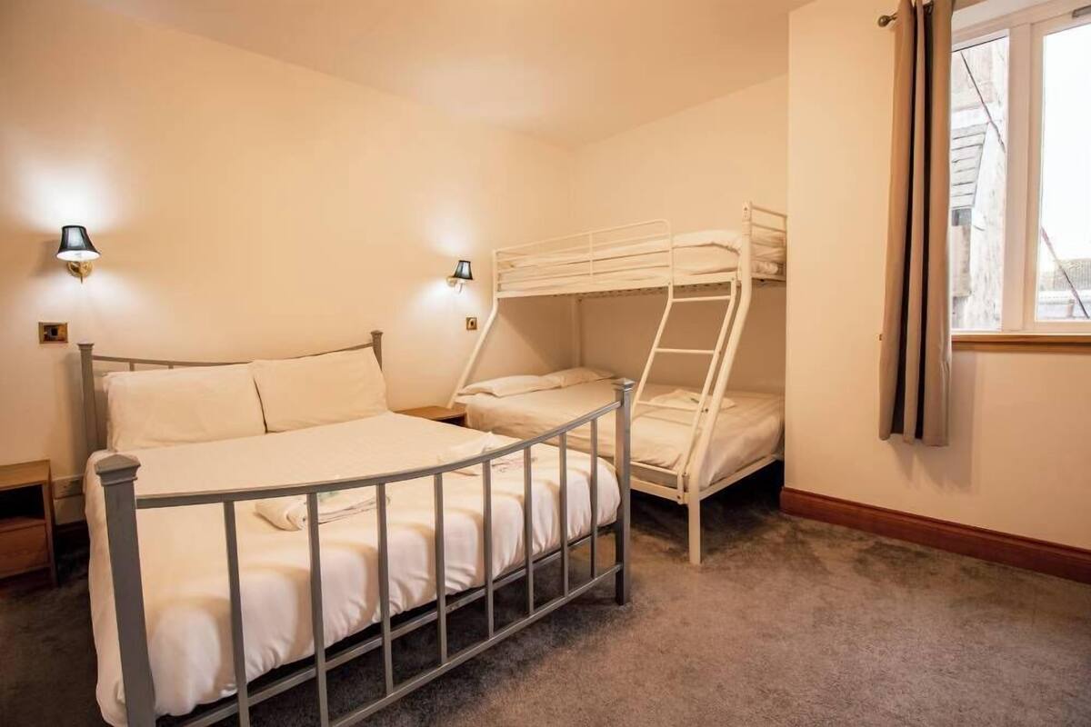 Habitación con literas, dos lámparas de noche y una ventana.
