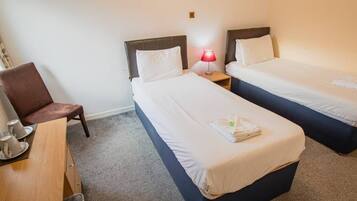 A hotel room with two beds, a desk, and a chair.