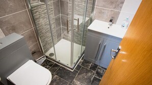 Een moderne badkamer met een glazen douchecabine, een toilet en een wastafelmeubel met een wastafel.
