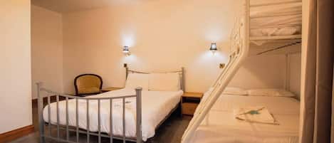 A bedroom with a single bed, a chair, a nightstand, and a bunk bed.