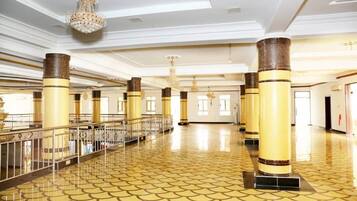 A spacious lobby with high ceilings, ornate chandeliers, and a patterned floor.