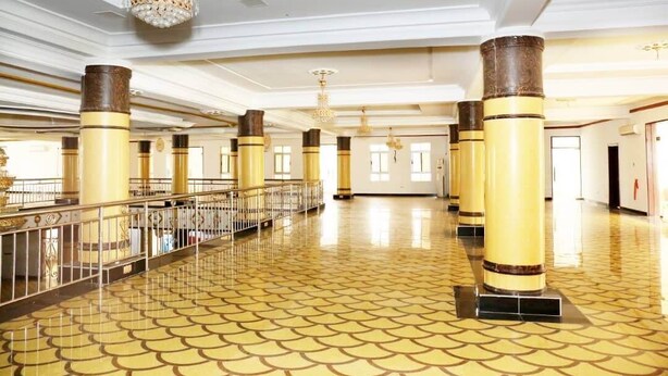 A spacious lobby with high ceilings, ornate chandeliers, and a patterned floor.