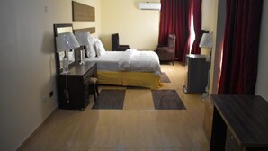 A hotel room with a bed, desk, chair, and a small table.