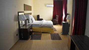 A hotel room with a bed, desk, chair, and a small table.