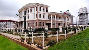 A large, multi-story building with a symmetrical facade, featuring a central entrance with columns and a balcony.