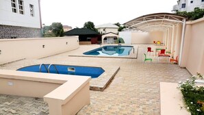 A rooftop pool area with two pools, outdoor seating, and a covered patio.