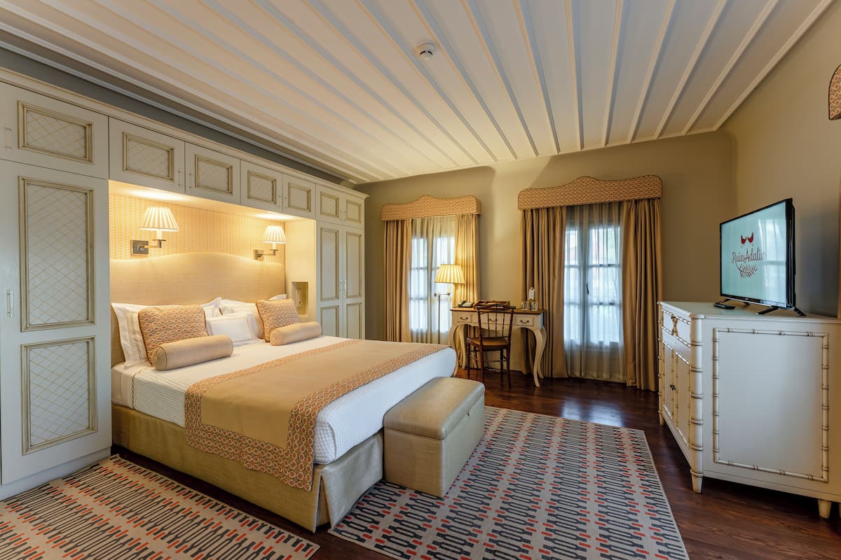 Une chambre spacieuse avec un grand lit, des lampes de chevet, un bureau et une télévision.