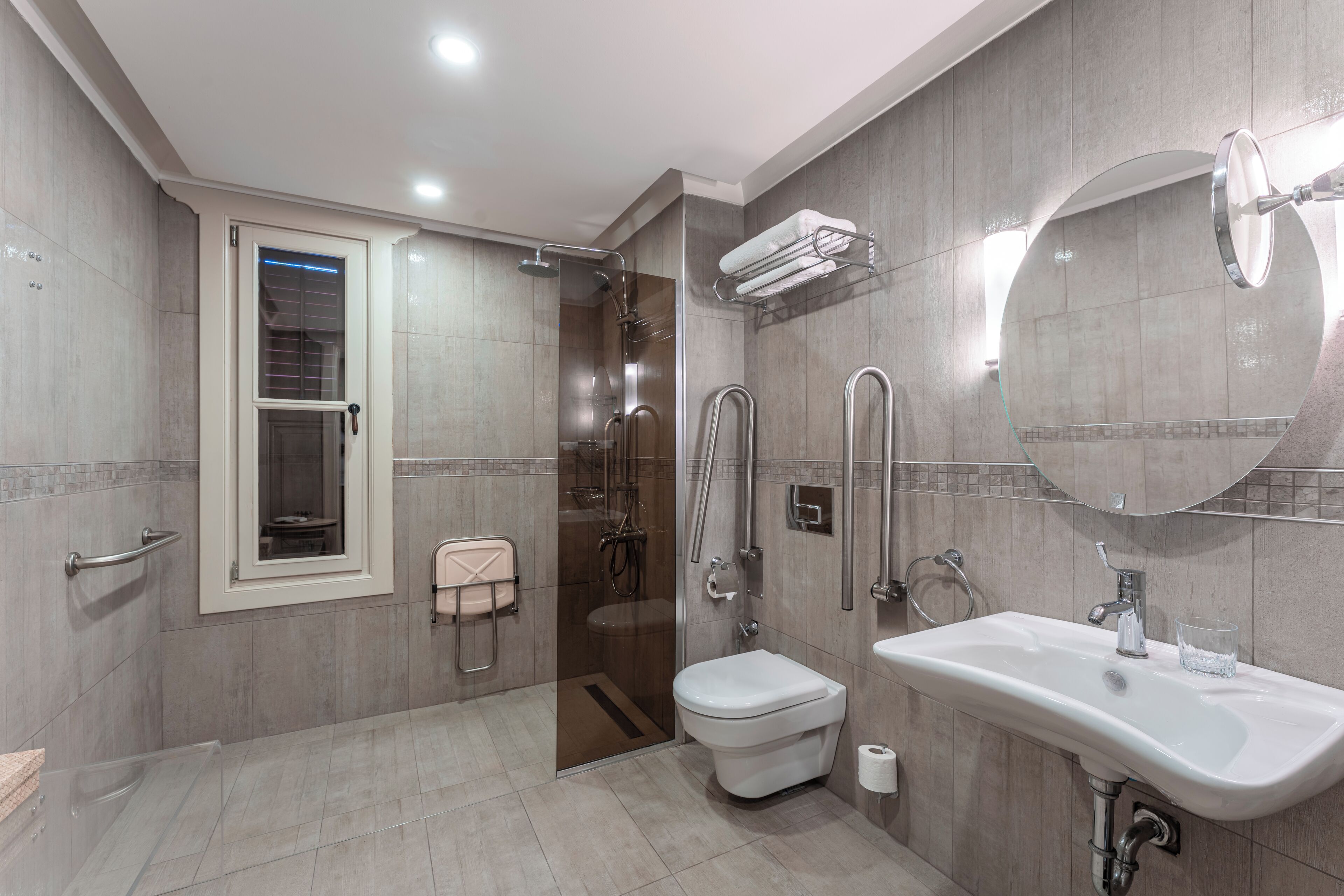 A modern bathroom with a glass-enclosed shower, a toilet, a sink, and a mirror.