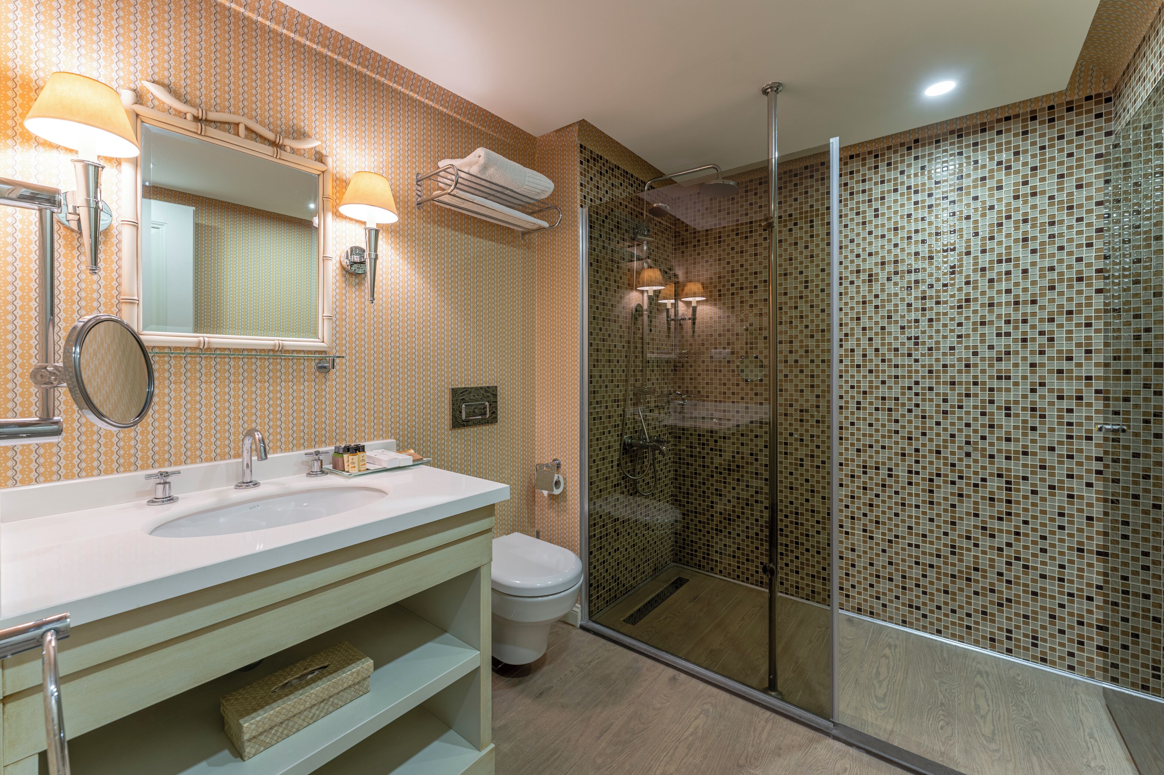 A modern bathroom with a large sink, mirror, and a glass-enclosed shower.