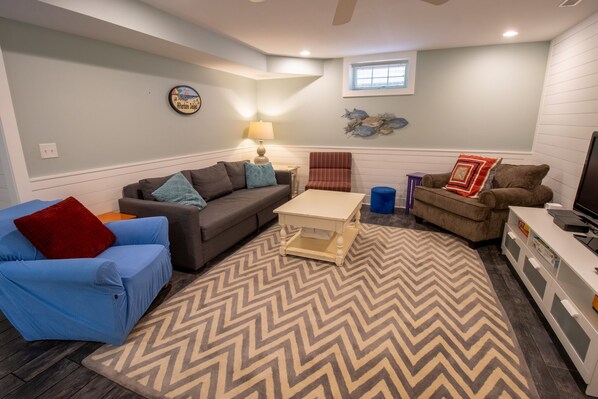A living room with a sofa, armchairs, a coffee table, and a television. - The Get Awave is the real deal, everything you want in a beach house (Michigan City)