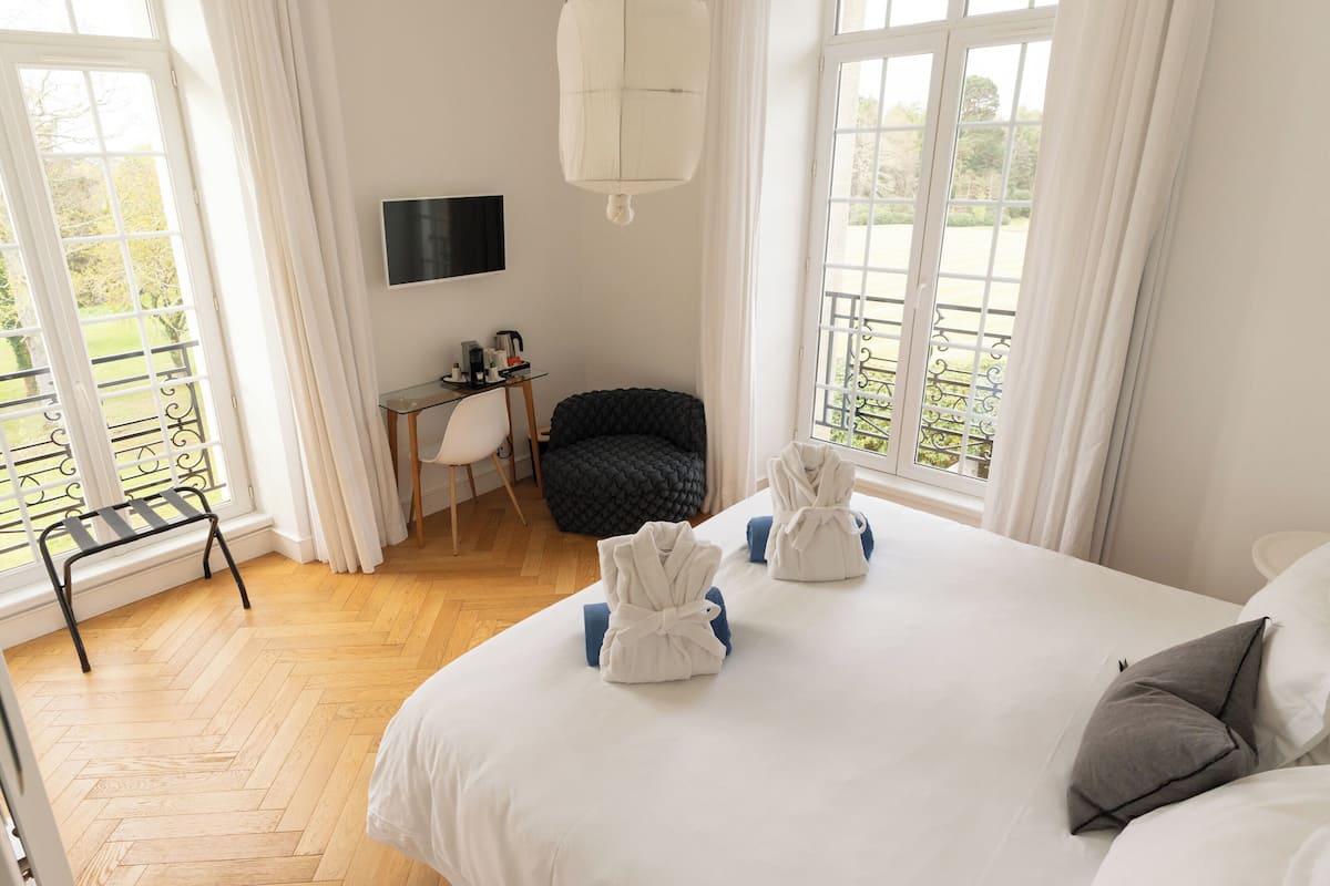 A hotel room with a bed, a desk, a chair, and a balcony with a view.