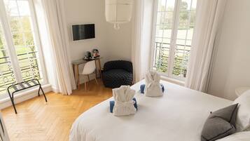 Camera d'albergo con un letto, una scrivania, una sedia e un balcone con vista.