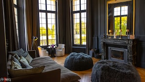 A room with a large window, a fireplace, a sofa, and a leopard print chair.