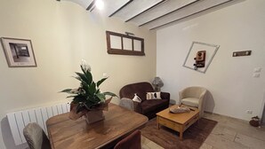Una sala de estar con una mesa de comedor de madera, dos sofás, una mesa de centro y una planta en maceta.