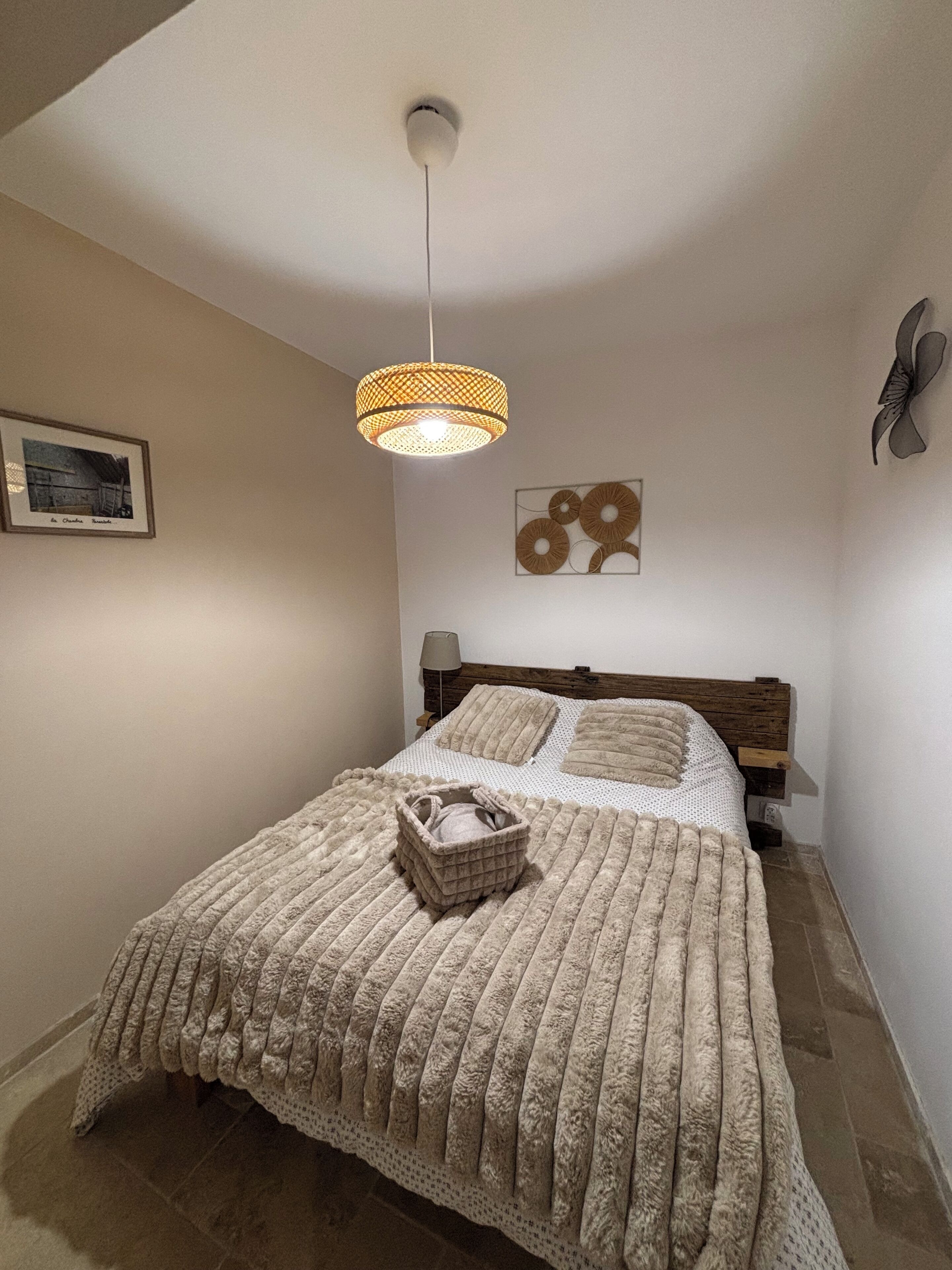 Un dormitorio con una cama grande, una lámpara colgante, un cuadro enmarcado y un adorno de pared.