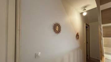 Ein Flur mit Lichtschalter, einer Tür und zwei Wanddekorationen im Sonnenstrahl-Design.