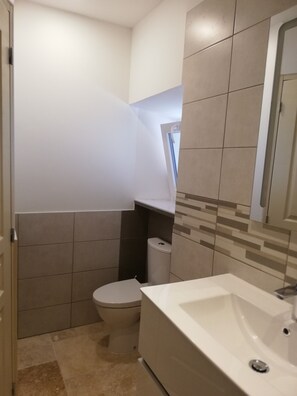 Een badkamer met toilet, wastafel en bad.