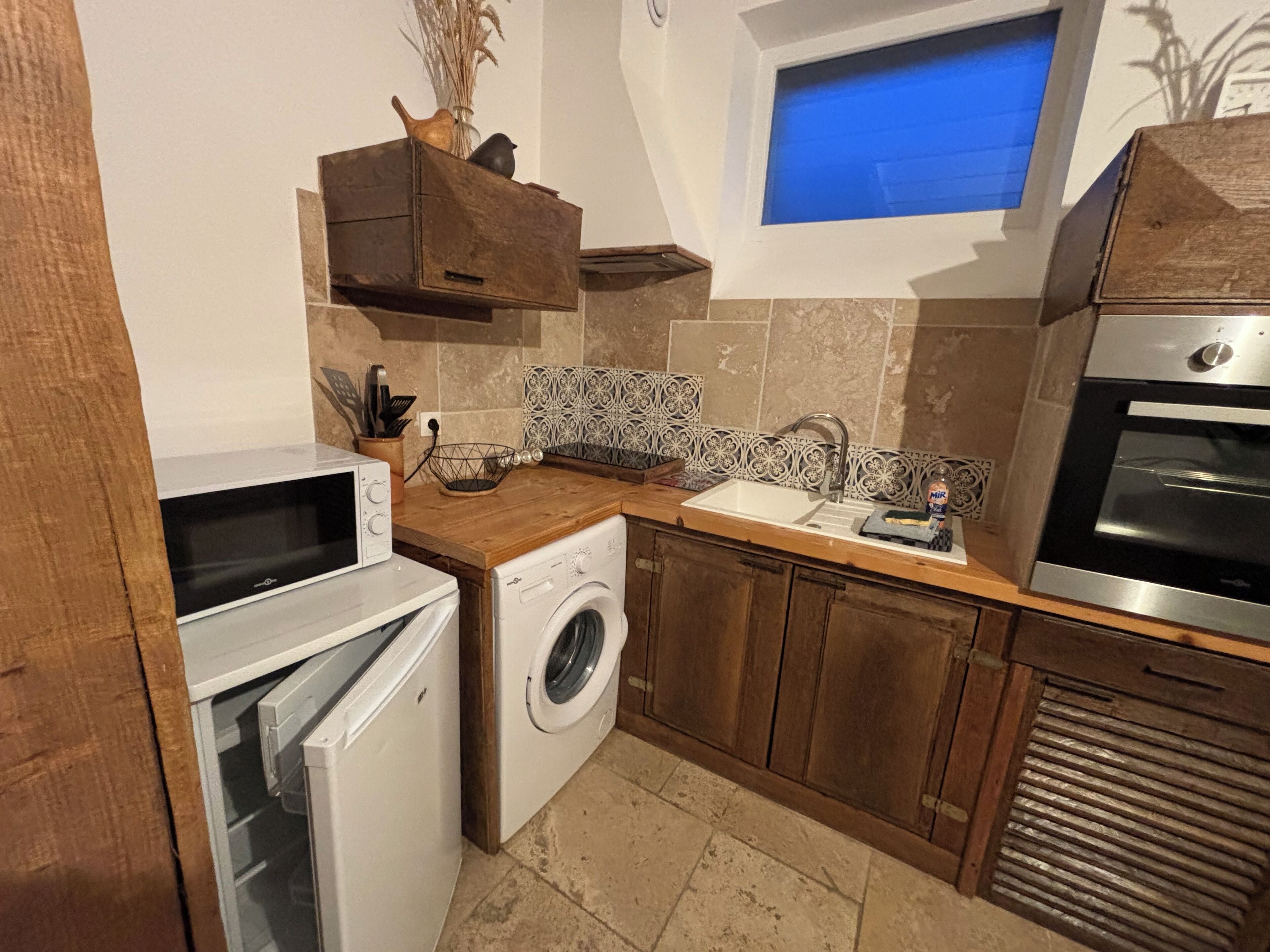 Eine kleine Küche mit Waschmaschine, Mikrowelle, Spüle und Backofen.