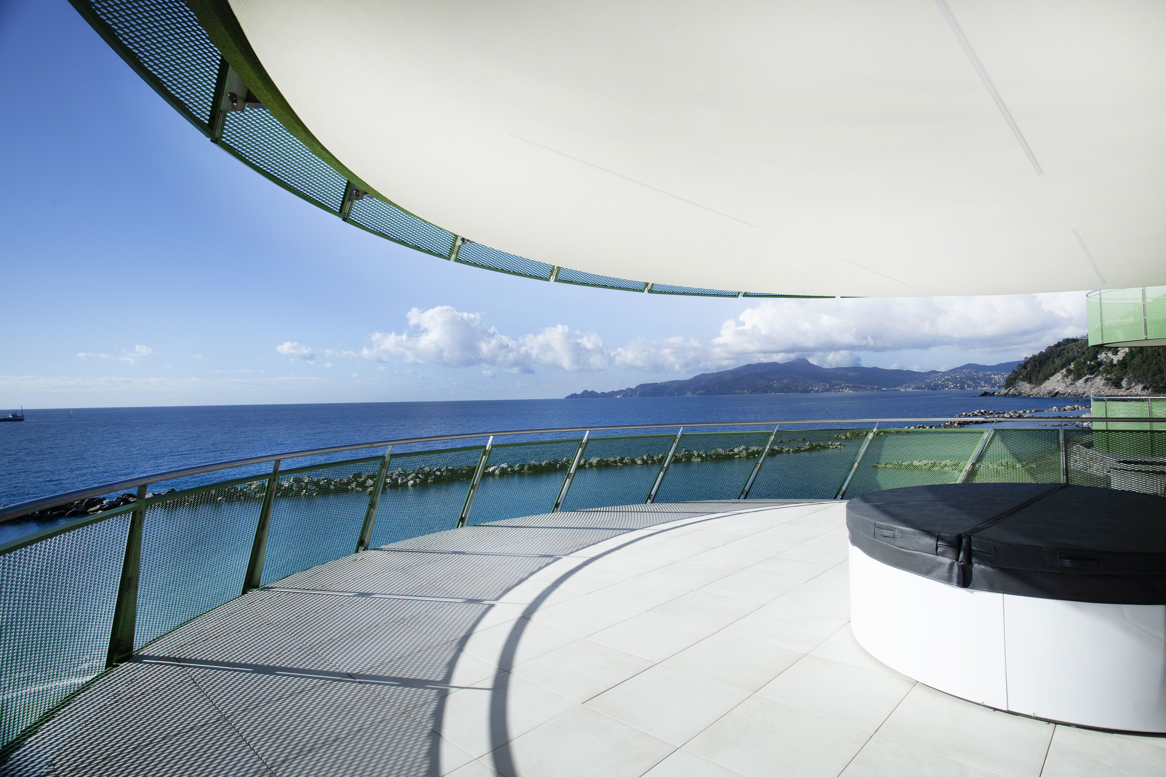A curved outdoor deck with a view of the sea and distant mountains.