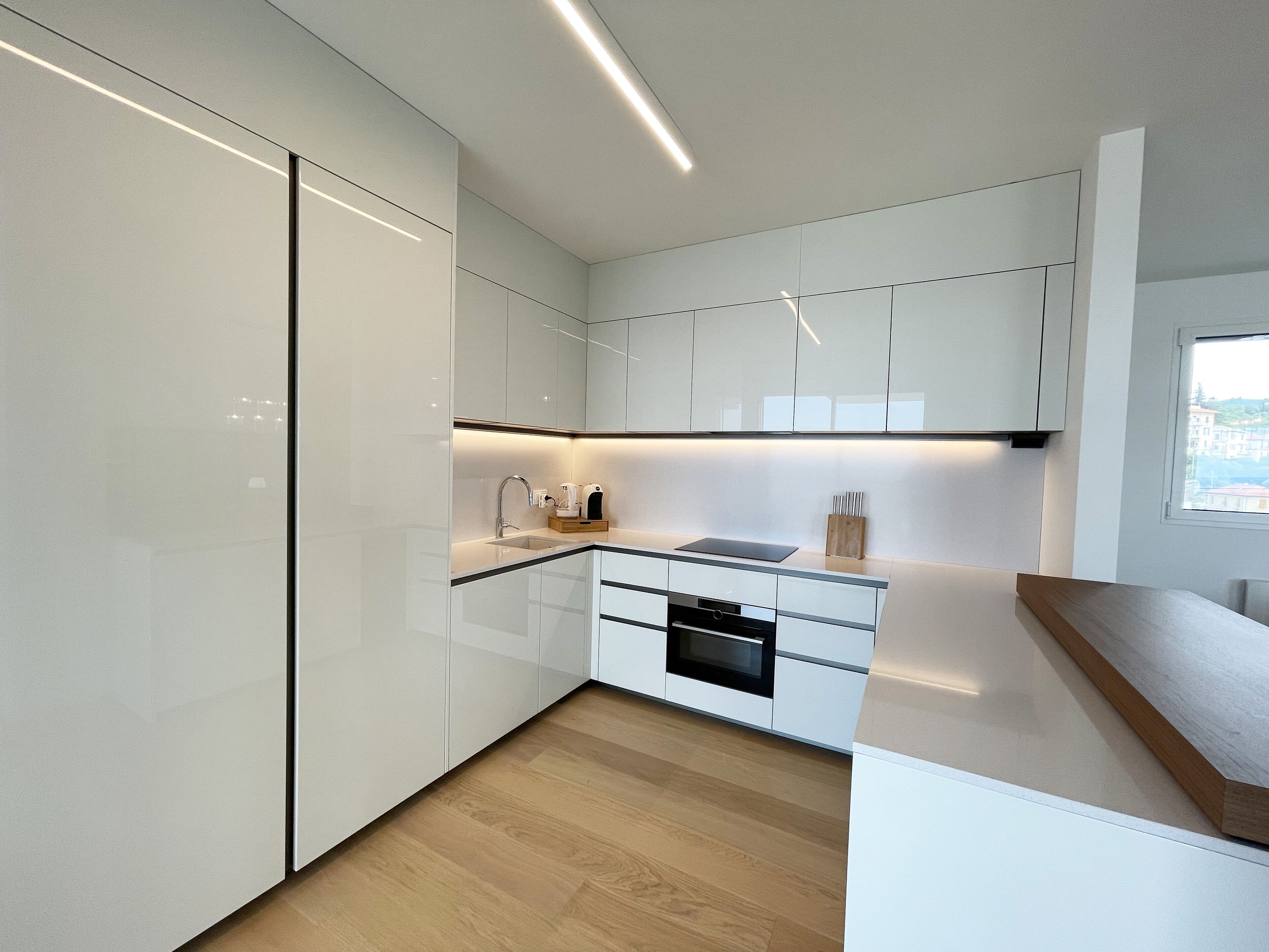 A modern kitchen with white cabinetry, a wooden countertop, and a built-in oven.