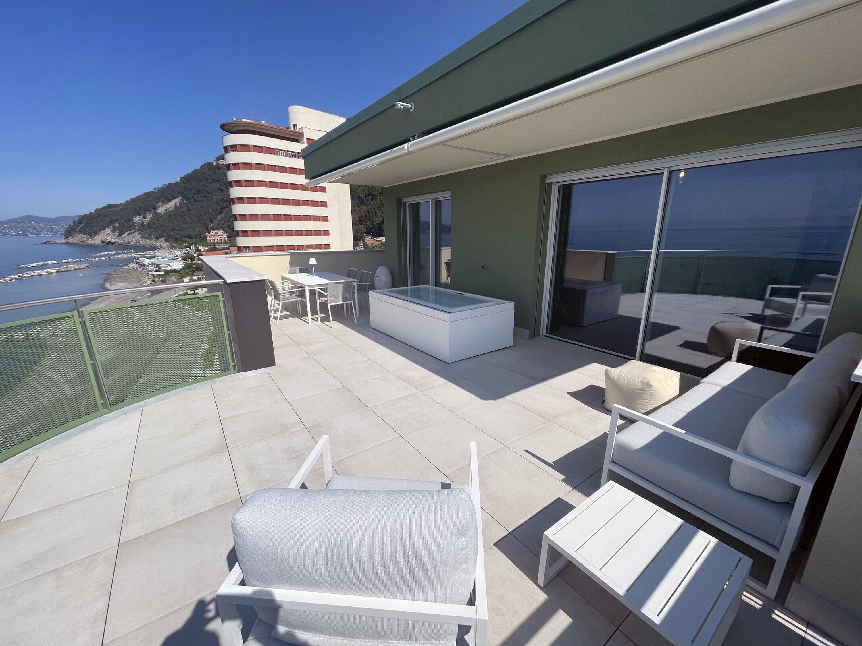 Un balcón con mesa de billar, sillones de descanso y puerta de vidrio que da a una terraza.