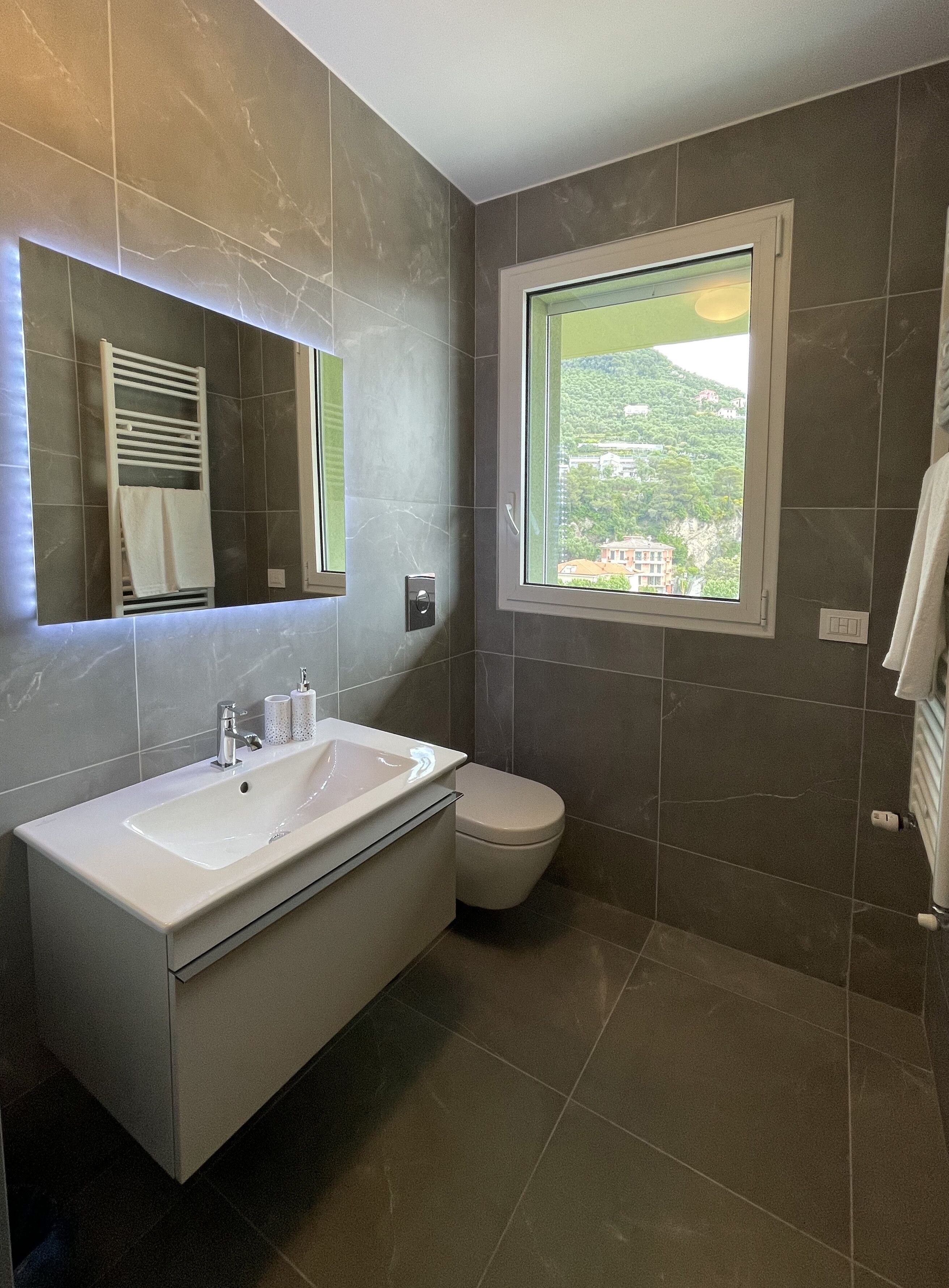 A modern bathroom with a large sink, mirror, and window.