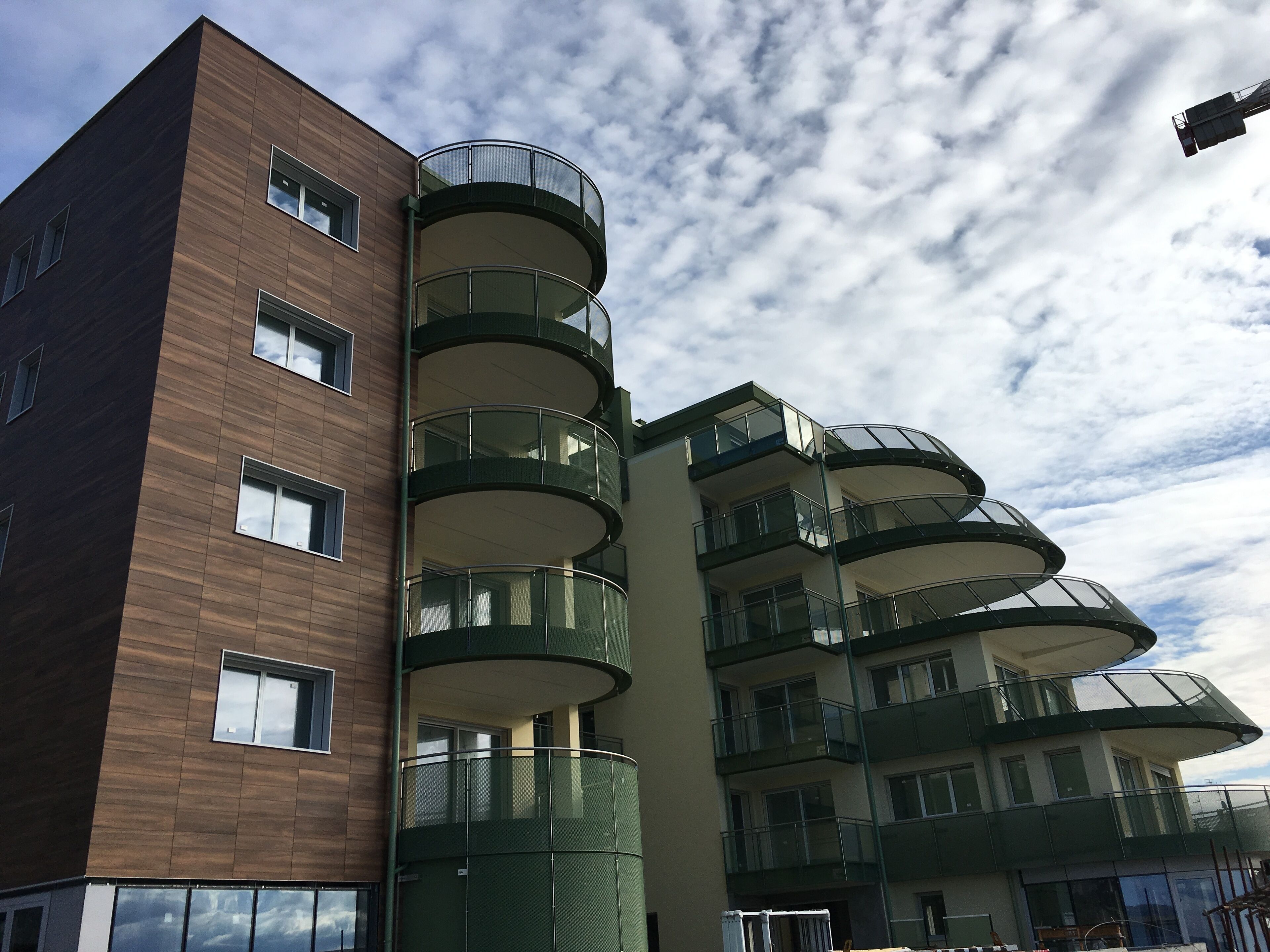 A multi-story building with a modern architectural design, featuring balconies with glass railings and a mix of window styles.
