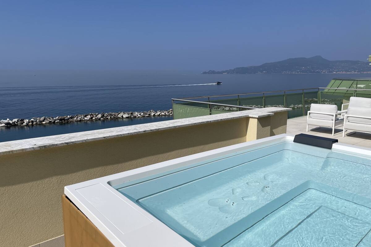 A rooftop pool with a clear view of the sea and distant hills.