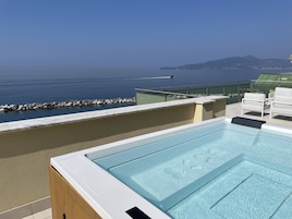 Una piscina en la azotea con vistas despejadas al mar y colinas distantes.