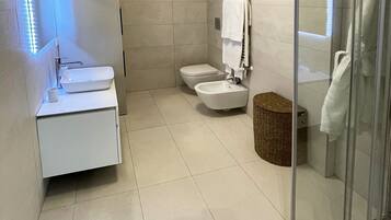 A modern bathroom with a glass shower enclosure, a white sink, and a toilet.