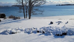 A snowy landscape with a lake, trees, and a clear sky. -  The Lazy Acre: Waterfront cottage with unparalleled views of Smith's Bay. (Prince Edward)