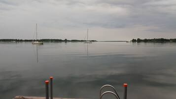 Een rustig meer met boten en een steiger op de voorgrond.