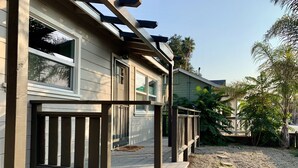 A house with a wooden deck, a pergola, and a gravel pathway.