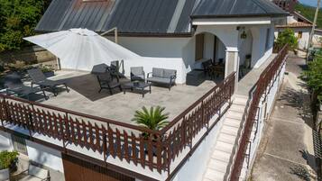 Un patio en la azotea con mobiliario exterior, una zona cubierta y una escalera que lleva al nivel superior.