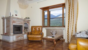 Een woonkamer met een open haard, een leren fauteuil en een bank.