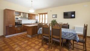 Une cuisine avec des meubles en bois, un four à micro-ondes et une cuisinière. On y trouve une table à manger avec des chaises et un lustre au-dessus.