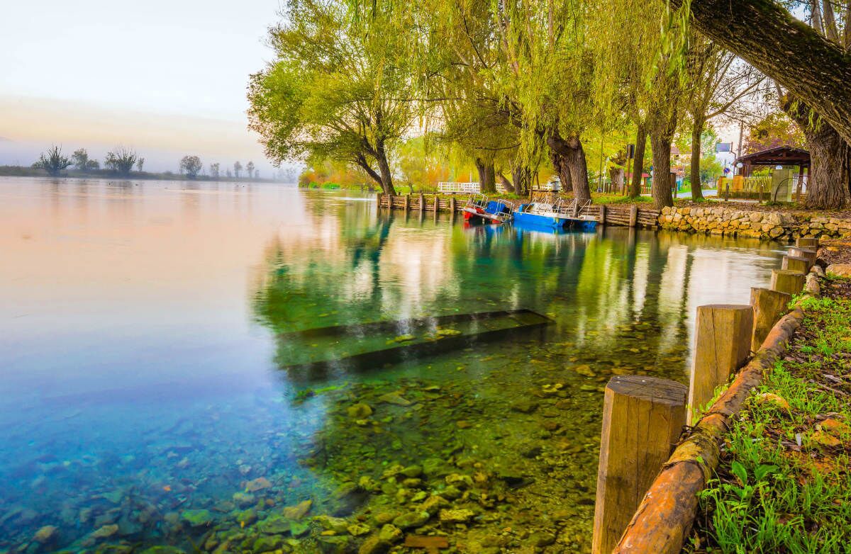Ein ruhiger See mit klarem Wasser, Holzanlegestellen und Booten.
