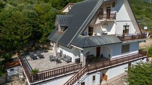 Un bâtiment à deux étages doté d’un balcon, d’un espace extérieur aménagé pour s’asseoir et offrant une vue sur la végétation environnante.
