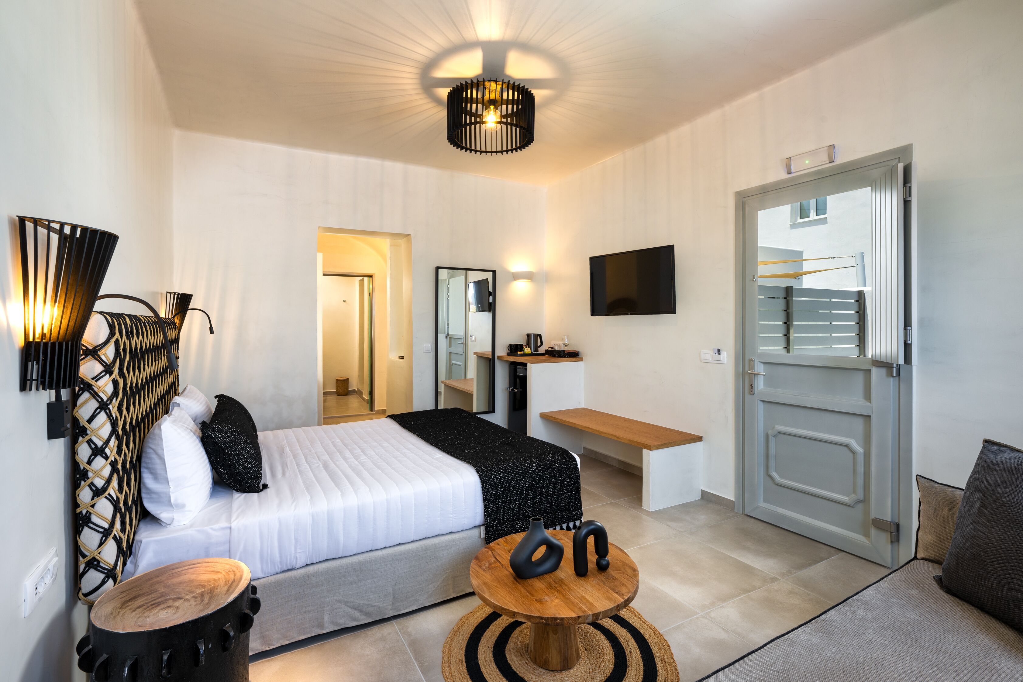 A modern hotel room with a bed, bedside table, and a TV mounted on the wall.