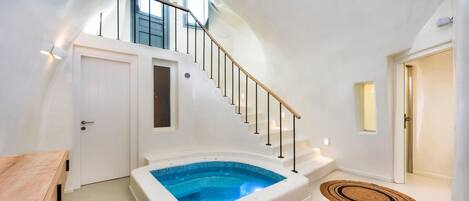Un intérieur moderne avec un jacuzzi intégré, un escalier et une table en bois.