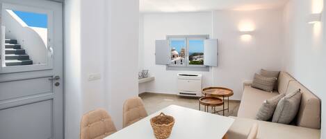 Ein modernes Wohnzimmer mit einer Couch, einem Esstisch mit Stühlen, einem an der Wand befestigten Fernseher und einer Treppe, die zu einem Außenbereich führt.