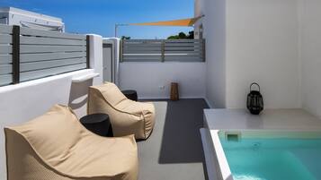 Terraza en la azotea con piscina, paredes blancas y dos sillones color beige.