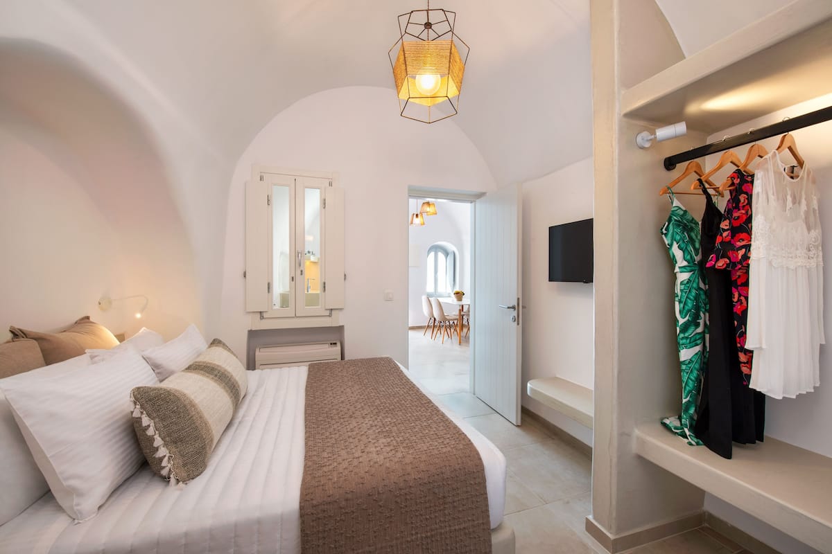 Ein Schlafzimmer mit Bett, Kleiderschrank, Spiegel und einer Tür zu einem Essbereich.