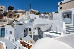 Un edificio blanco con piscina, asientos al aire libre y una escalera que lleva a un nivel superior.