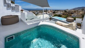A rooftop infinity pool with a view of the sea and cityscape. - Hill Suites (Santorini)
