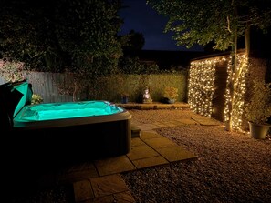 A hot tub in a garden with a wooden fence and potted plants. - Elckys Holiday HOT TUB Lodge York (York)