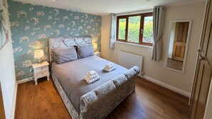 Un dormitorio con cama, mesitas de noche, ventana y radiador.