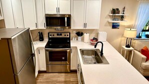 A modern kitchen with white cabinets, stainless steel appliances, and a built-in microwave.