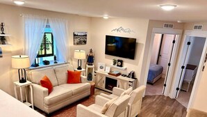 A living room with a sofa, armchairs, a TV, and a fireplace.