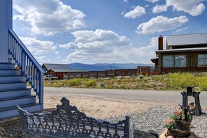 A building with a blue staircase, a bench, and a metal planter with flowers. - 2BR Mountain Retreat - Near Mineral Trail, Balcony (Leadville)